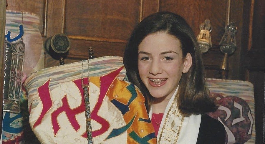 Bat mitzvah girl with braces holds Torah.