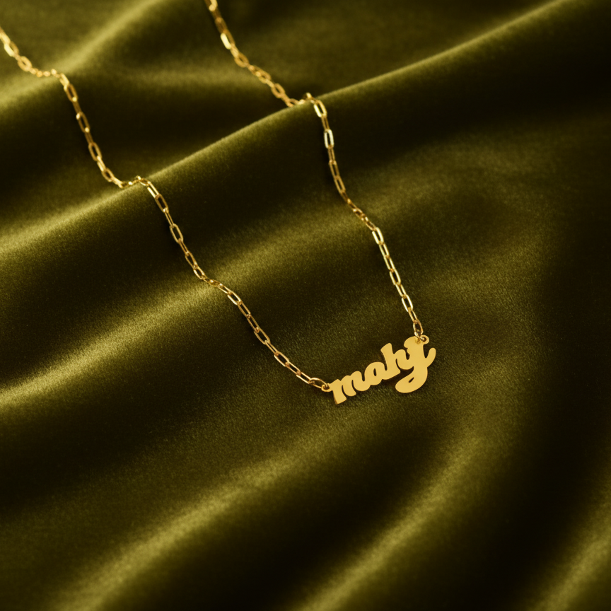 Gold necklace with 'mahj' as in mahjong pendant on a green satin background
