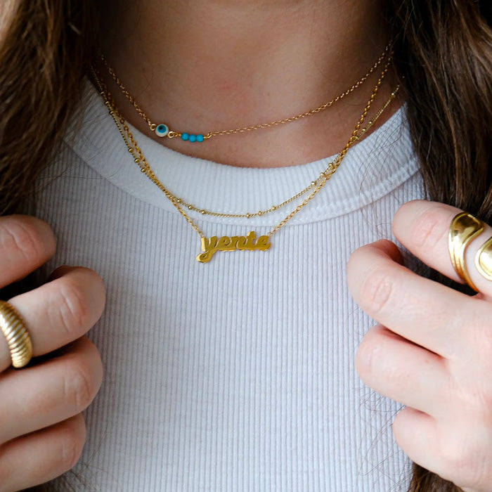 Close up of woman with brown hair wearing layered gold necklaces.